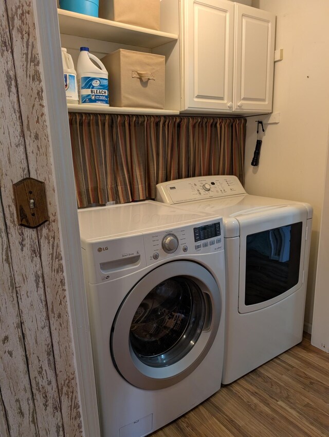 laundry area with washer and clothes dryer, wood finished floors, and cabinet space