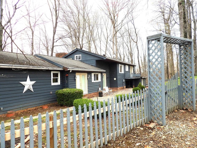 view of front of house featuring a shingled roof, fence, and a chimney