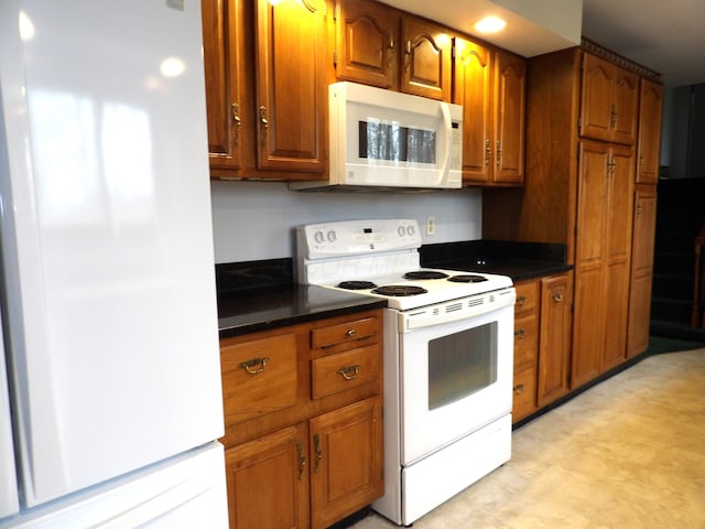 kitchen featuring white appliances, dark countertops, and brown cabinetry