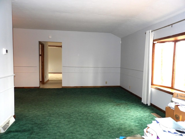 spare room with baseboards, carpet, lofted ceiling, and visible vents