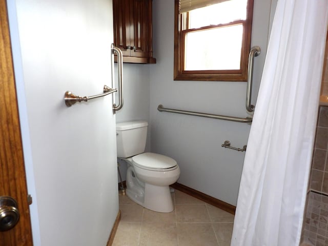 bathroom featuring baseboards, tile patterned floors, toilet, and tiled shower