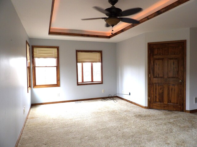 unfurnished room featuring baseboards, ceiling fan, carpet, and a tray ceiling