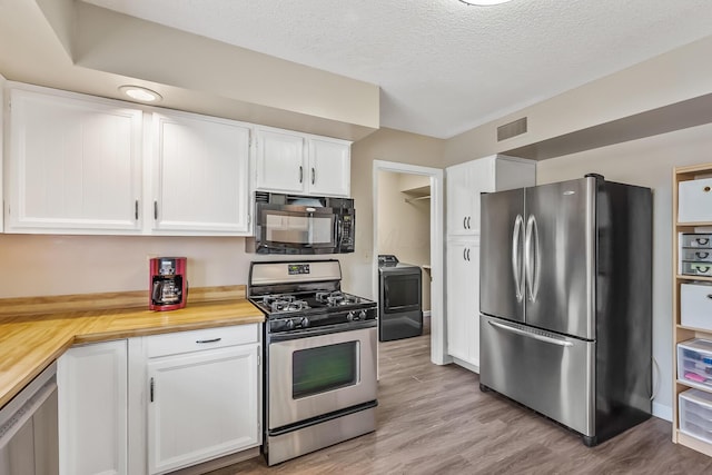 kitchen with washer / clothes dryer, visible vents, wood counters, stainless steel appliances, and white cabinetry