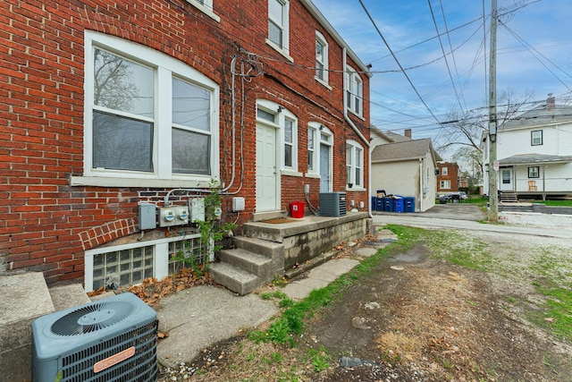 view of side of home featuring brick siding and central air condition unit