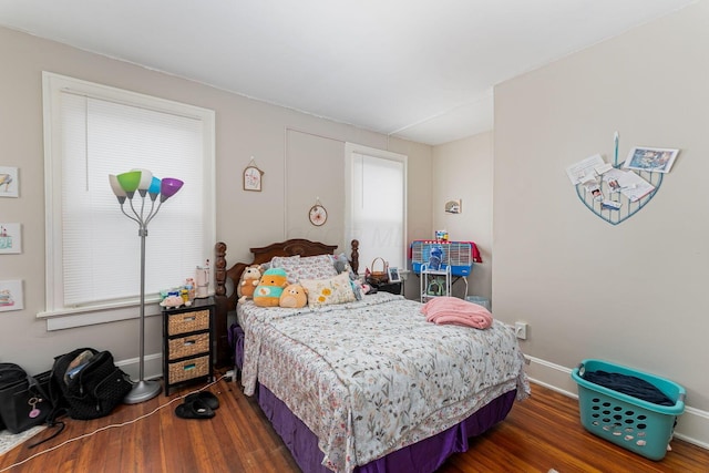 bedroom with wood finished floors, baseboards, and multiple windows