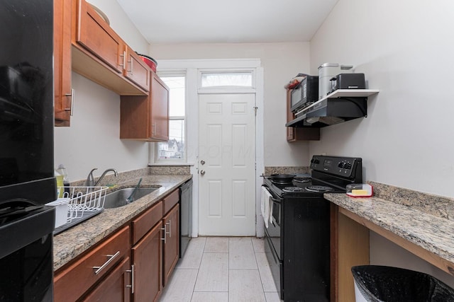 kitchen featuring a sink, under cabinet range hood, brown cabinets, black appliances, and light stone counters