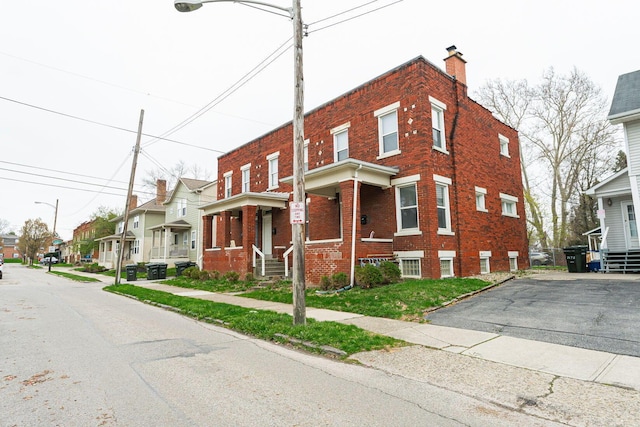 multi unit property featuring a chimney, a residential view, and brick siding