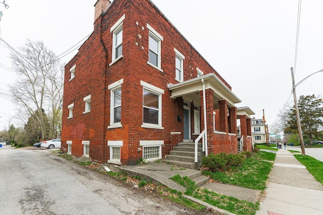 view of front of home featuring brick siding and a chimney