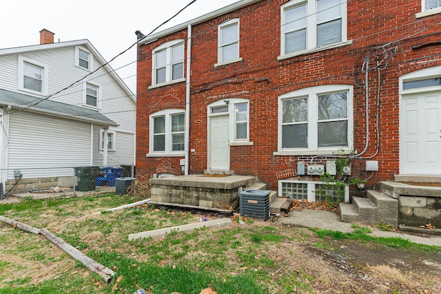 rear view of property with brick siding, central air condition unit, and fence