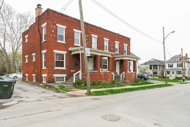 townhome / multi-family property with a chimney and brick siding