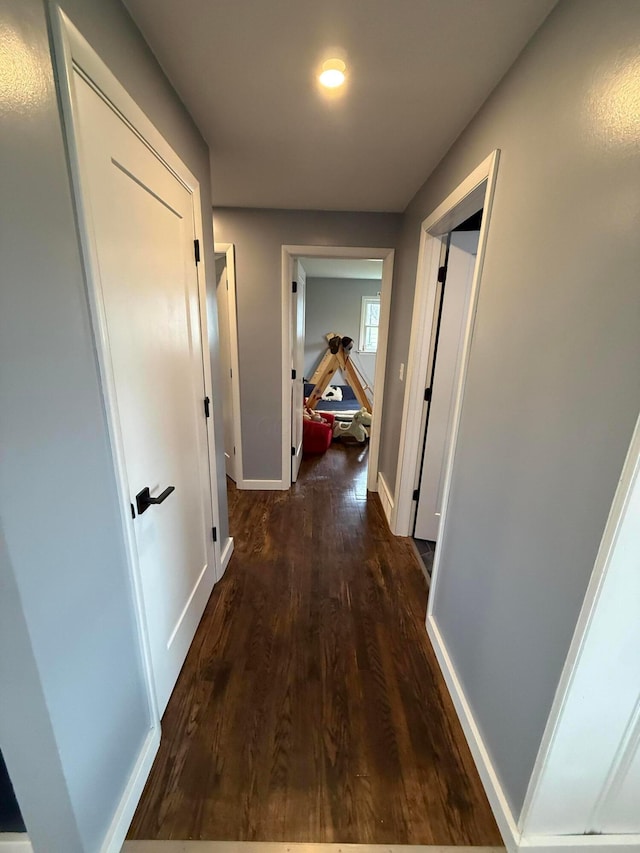 hallway featuring dark wood finished floors and baseboards