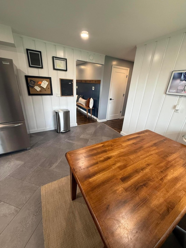 bedroom with freestanding refrigerator, a decorative wall, and baseboards