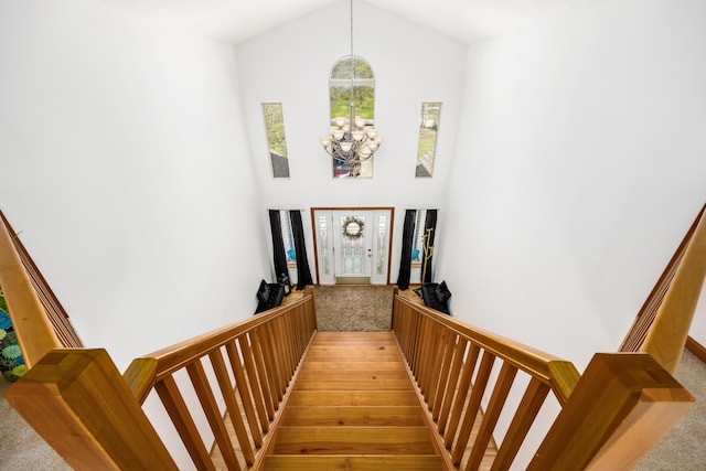 staircase with carpet, a chandelier, and high vaulted ceiling