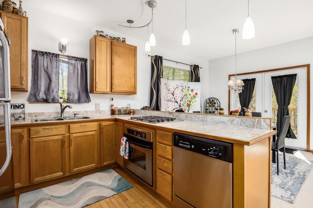 kitchen with a peninsula, a sink, appliances with stainless steel finishes, and brown cabinets