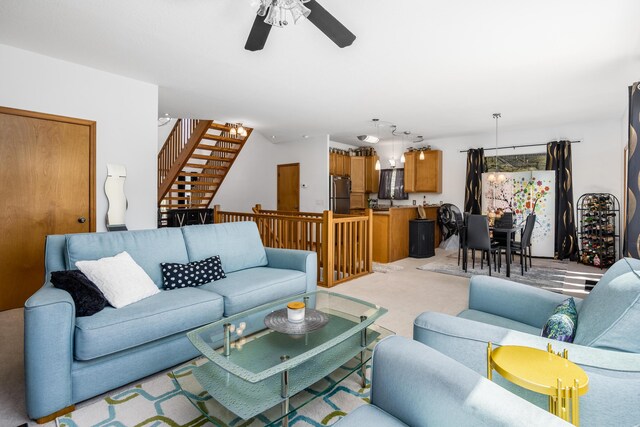 living area featuring stairs, ceiling fan, and light carpet