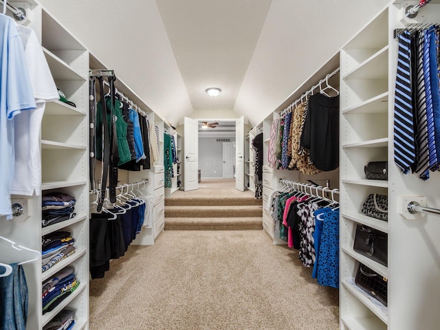 walk in closet with vaulted ceiling and carpet flooring