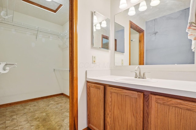 5955 Glen Village Dr, Dublin, OH 43016 - bathroom featuring a textured ceiling, vanity, a ceiling fan, a spacious closet, and baseboards