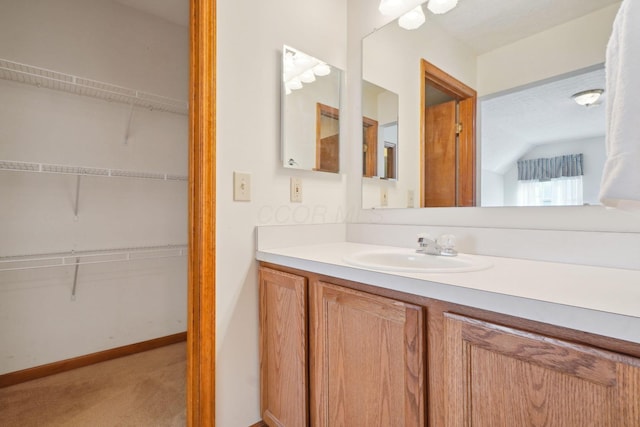 5955 Glen Village Dr, Dublin, OH 43016 - bathroom with baseboards, a walk in closet, vanity, and lofted ceiling