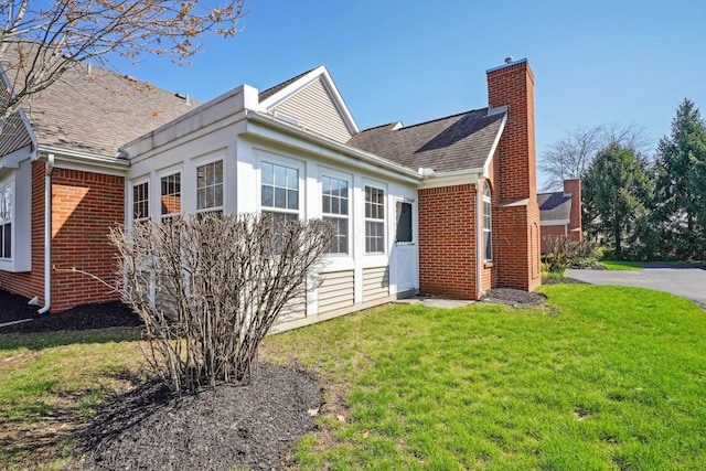 5955 Glen Village Dr, Dublin, OH 43016 - view of home's exterior featuring a shingled roof, a chimney, a lawn, and brick siding