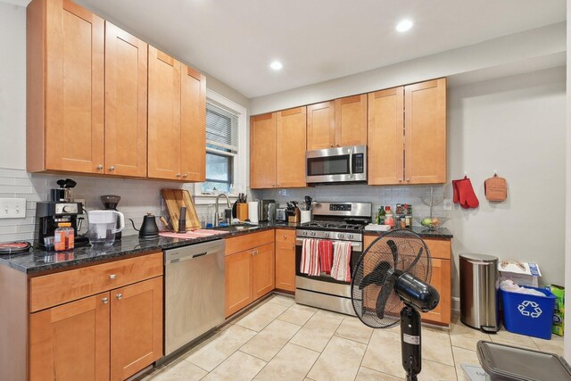 1287 City Park Ave, Columbus, OH 43206 - kitchen with appliances with stainless steel finishes, a sink, light tile patterned flooring, tasteful backsplash, and dark stone countertops