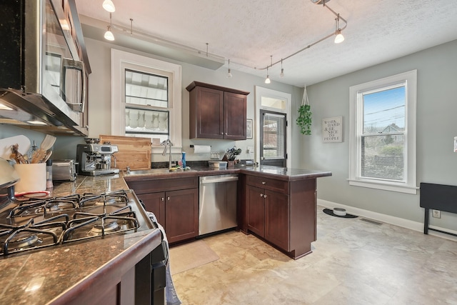 1287 City Park Ave, Columbus, OH 43206 - kitchen with stainless steel appliances, a sink, a peninsula, dark brown cabinetry, and a textured ceiling