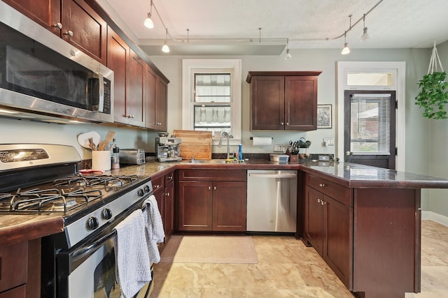 1287 City Park Ave, Columbus, OH 43206 - kitchen with stainless steel appliances, a sink, a peninsula, track lighting, and tile countertops