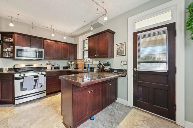 1287 City Park Ave, Columbus, OH 43206 - kitchen featuring stainless steel appliances, a peninsula, light marble finish floors, a sink, and track lighting