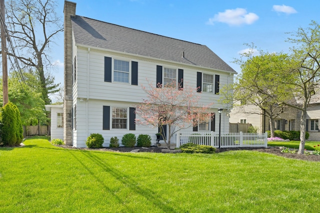 view of front of property with fence, a chimney, roof with shingles, and a front yard