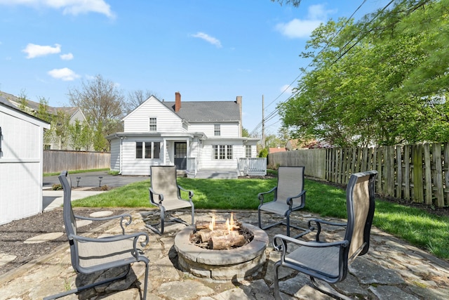rear view of house featuring a chimney, a fenced backyard, a yard, a patio area, and a fire pit