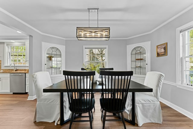 dining area with light wood-style flooring, ornamental molding, and a healthy amount of sunlight