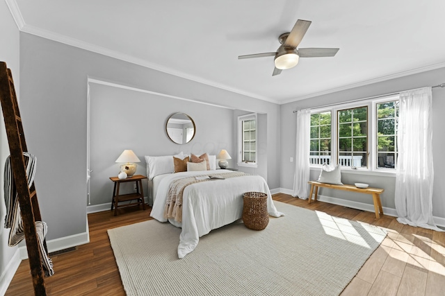 bedroom featuring dark wood finished floors, ceiling fan, baseboards, and ornamental molding