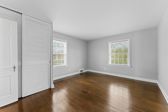 unfurnished bedroom with baseboards, wood finished floors, and multiple windows