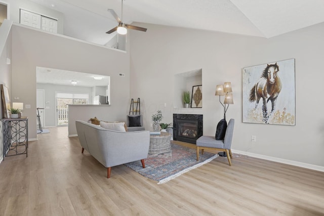 living room with ceiling fan, a premium fireplace, baseboards, and wood finished floors