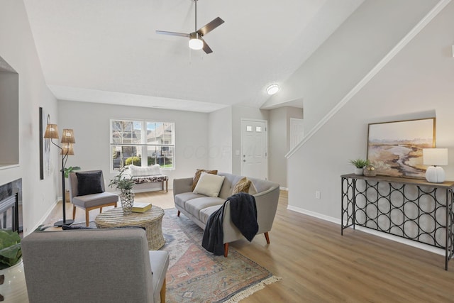 living area with ceiling fan, a tile fireplace, wood finished floors, and baseboards