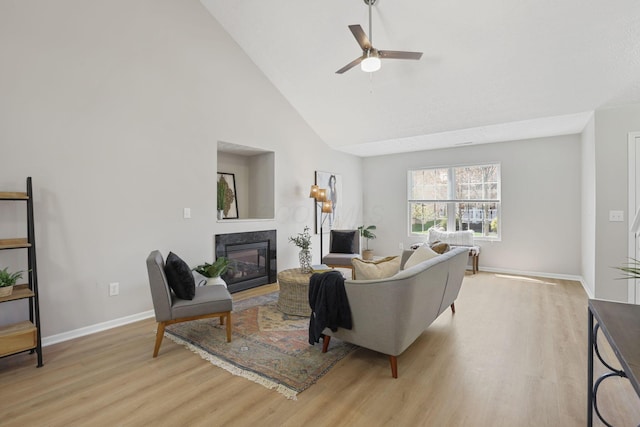living room with light wood finished floors, a fireplace, a ceiling fan, and baseboards