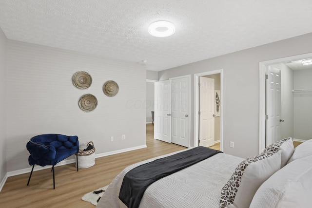 bedroom with a closet, baseboards, wood finished floors, and a textured ceiling