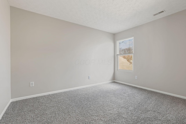 unfurnished room with carpet flooring, visible vents, baseboards, and a textured ceiling