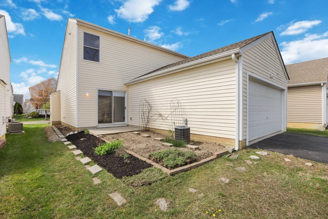 back of house with a lawn, driveway, central AC, and an attached garage