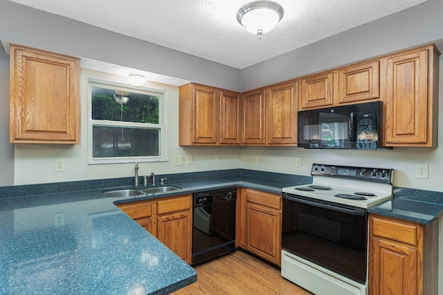 5516 Latrobe St, Westerville, OH 43081 - kitchen with black appliances, a sink, light wood finished floors, dark countertops, and a textured ceiling