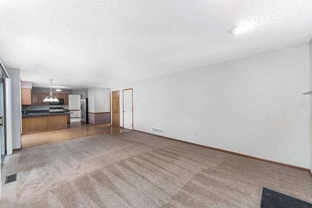5516 Latrobe St, Westerville, OH 43081 - unfurnished living room featuring a textured ceiling, dark colored carpet, a sink, and baseboards