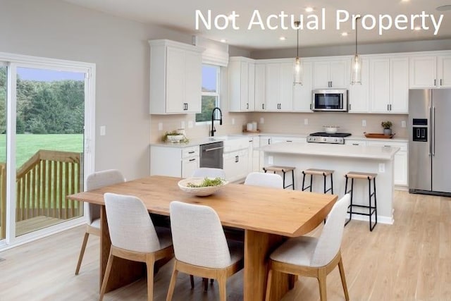 kitchen with light wood-style flooring, a center island, white cabinets, a kitchen bar, and appliances with stainless steel finishes