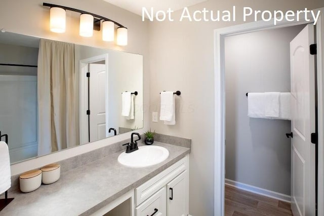 bathroom with vanity, baseboards, and wood finished floors