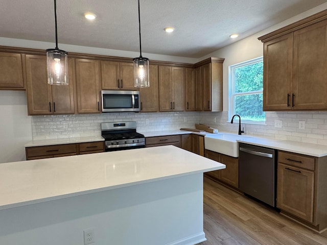 3441 Tender Ave Lot 7157, Powell, OH 43065 - kitchen featuring appliances with stainless steel finishes, light wood-style floors, backsplash, decorative light fixtures, and a textured ceiling