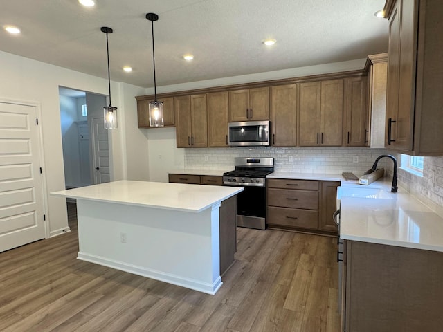 3441 Tender Ave Lot 7157, Powell, OH 43065 - kitchen with appliances with stainless steel finishes, wood finished floors, backsplash, recessed lighting, and a kitchen island