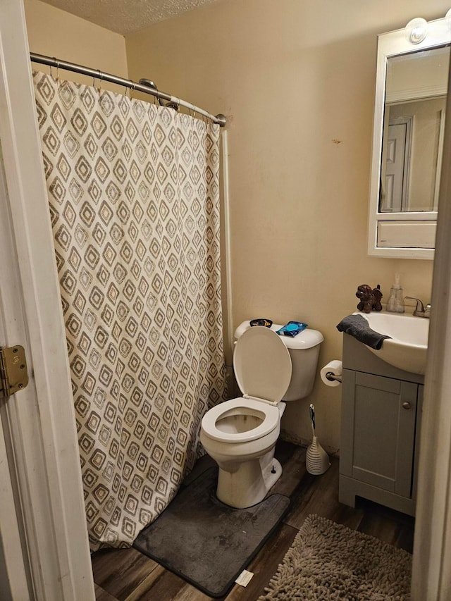 full bath with a shower with shower curtain, toilet, a textured ceiling, vanity, and wood finished floors