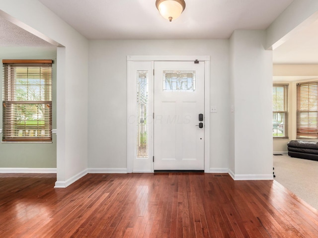 foyer entrance featuring baseboards, a wealth of natural light, and dark wood finished floors