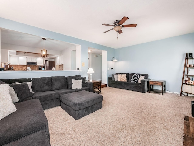 carpeted living room featuring ceiling fan and baseboards