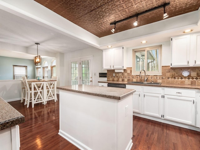 kitchen featuring dark wood-type flooring, a sink, white cabinetry, an ornate ceiling, and decorative backsplash