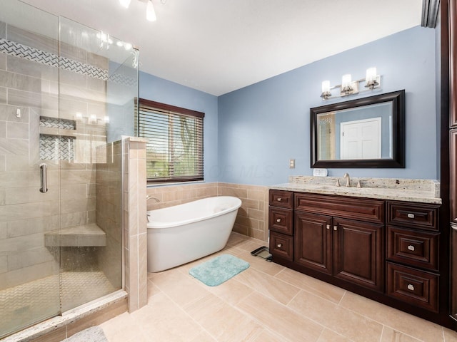 full bathroom with a shower stall, a soaking tub, vanity, and tile walls