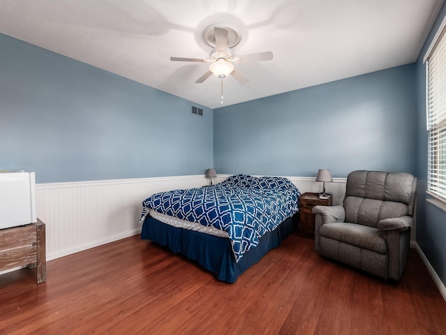 bedroom with visible vents, multiple windows, wainscoting, and wood finished floors